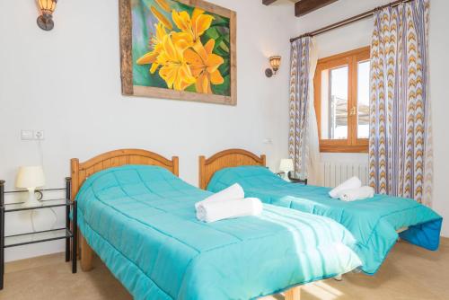 two beds in a bedroom with blue sheets and a window at Son Pujol in Montuiri