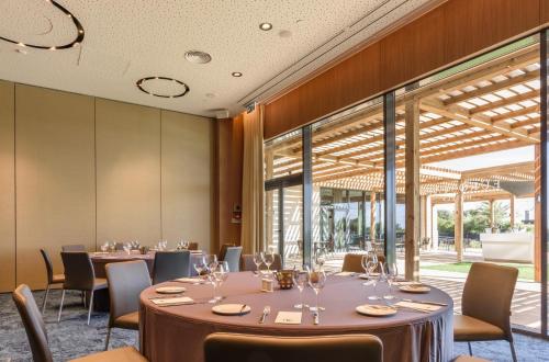 a dining room with tables and chairs and large windows at Eurostars Cascais in Cascais