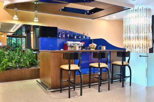 a bar with four stools at a blue counter at Central Park Hotel Modena in Modena