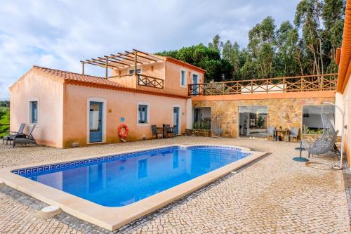 uma villa com piscina em frente a uma casa em Monte Soalheiro na Zambujeira do Mar