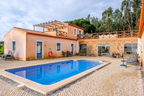 a villa with a swimming pool in front of a house at Monte Soalheiro in Zambujeira do Mar