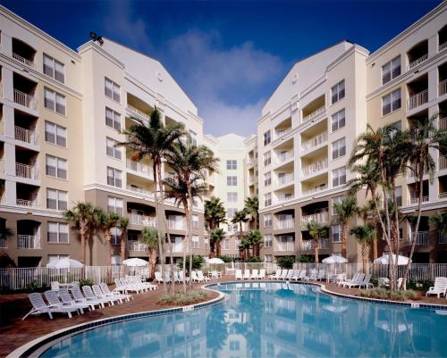 a pool in the courtyard of an apartment complex with palm trees at Vacation Village at Parkway in Orlando