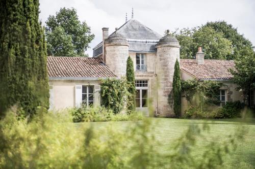 an old stone house with a tree in the foreground at Château Cordeillan-Bages in Pauillac