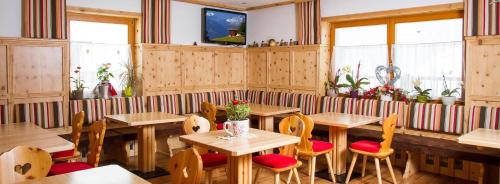 ein Restaurant mit Holztischen, Stühlen und Fenstern in der Unterkunft Landhaus St. Georg in Saalbach-Hinterglemm