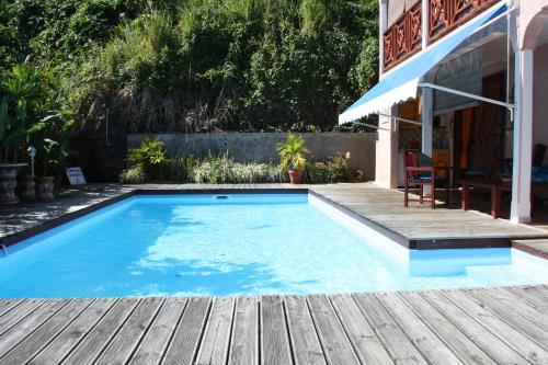 a swimming pool with a wooden deck next to a house at BEL Z 'IGUANE in Trois-Rivières