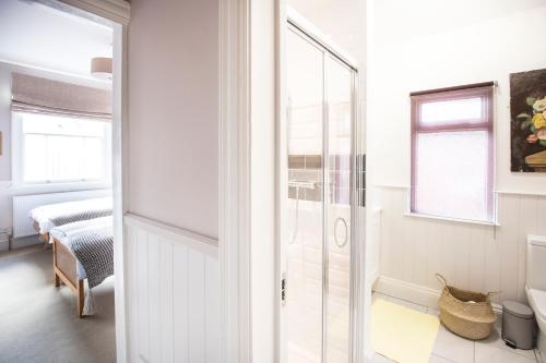 a bathroom with white walls and a glass door at Bournville House & Cafe in Birmingham