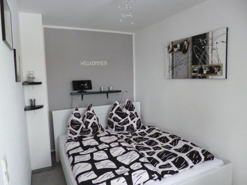 a white bedroom with a bed with black and white pillows at Appartement Brinkmann in Braunlage