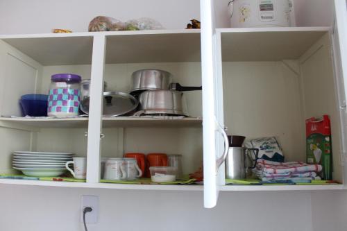 a white cabinet with dishes and pots and pans at Edicula Fundos in Jordãozinho