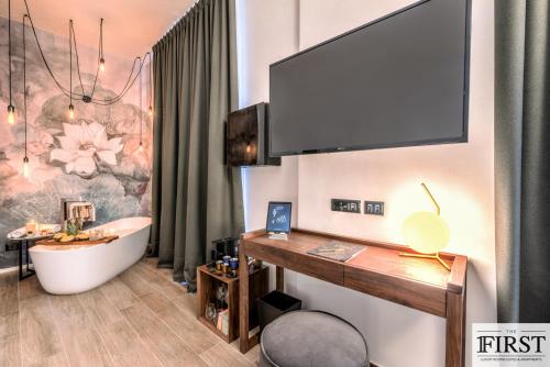 uma casa de banho com banheira e uma televisão na parede em La Spezia by The First - Luxury Rooms & Suites em La Spezia