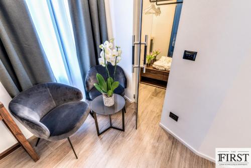 a room with two chairs and a table with a vase of flowers at La Spezia by The First - Luxury Rooms & Suites in La Spezia