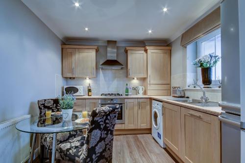 eine Küche mit Holzschränken und einem Tisch mit Stühlen in der Unterkunft Carrick Retreat - Donnini Apartments in Ayr