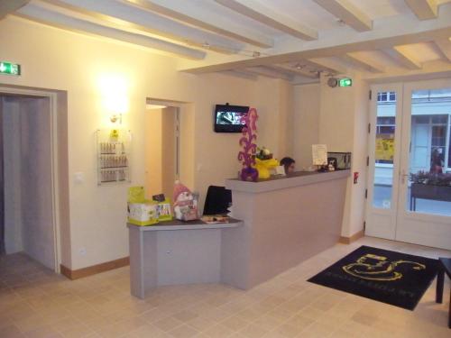 a room with a counter with a tv on a wall at Logis Hôtel Restaurant Le Puits Doré in Richelieu