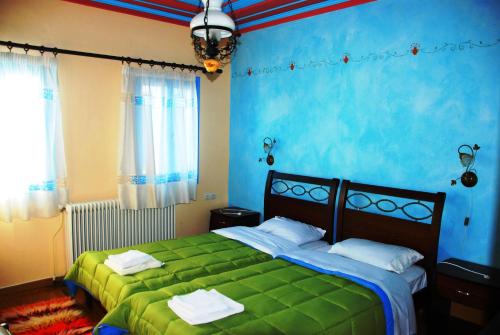 a bedroom with a green bed and blue walls at Hotel Ladias in Monodendri