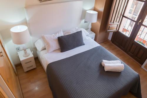 a bedroom with a large bed and two lamps at Apartamentos Elvira 21 in Granada