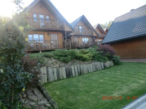 a large wooden house with a fence and a yard at Domki u Piotra in Solina