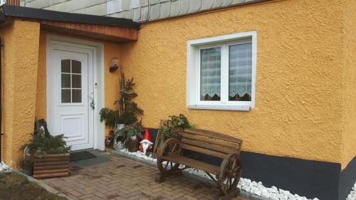 a bench sitting outside of a house with a dog at Ferienwohnung Panoramablick in Bärenstein
