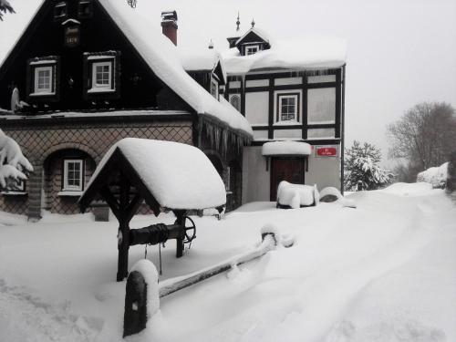 a house covered in snow in front of a house at Chalupa Medium in Krásná Lípa