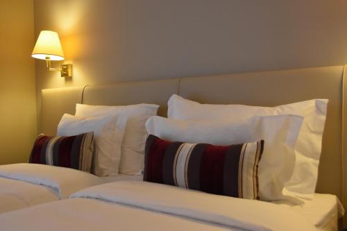 a bed with white pillows sitting next to a lamp at Hotel Suave Mar in Esposende