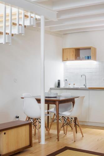 a kitchen with a wooden table and white chairs at Glory Days Lisbon Apartments in Lisbon