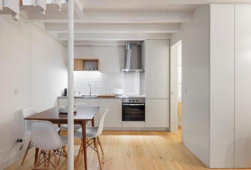 een witte keuken met een houten tafel en witte stoelen bij Glory Days Lisbon Apartments in Lissabon