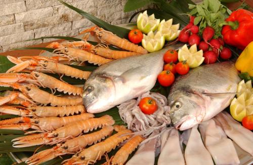 two fish and carrots next to a bunch of vegetables at Hotel Zurigo in Varazze