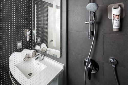 La salle de bains est pourvue d'un lavabo blanc et d'un miroir. dans l'établissement ibis London Greenwich, à Londres