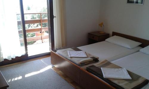 two beds in a room with a window at Apartments Pero in Kožino