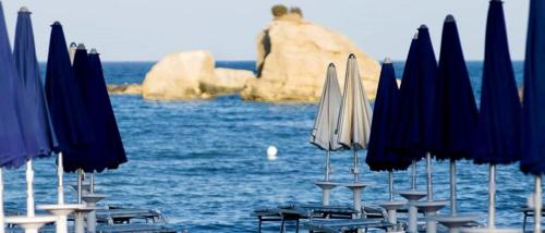 a group of tables and chairs with umbrellas and the ocean at Villa Lucia With Salt Pool in Fontane Bianche