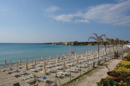 a beach with chairs and umbrellas and the ocean at Villa Lucia With Salt Pool in Fontane Bianche