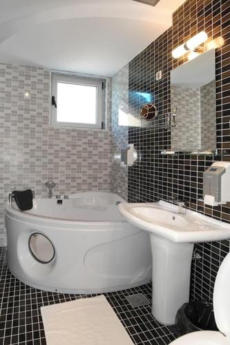 a bathroom with a white tub and a sink at Hotel Golf Luxury in Kruševac