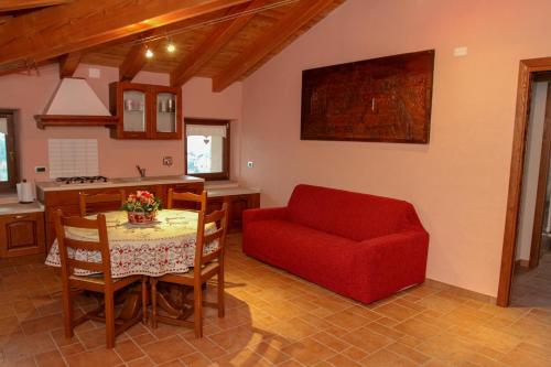 a living room with a table and a red chair at La Maison De Deni in Aymavilles