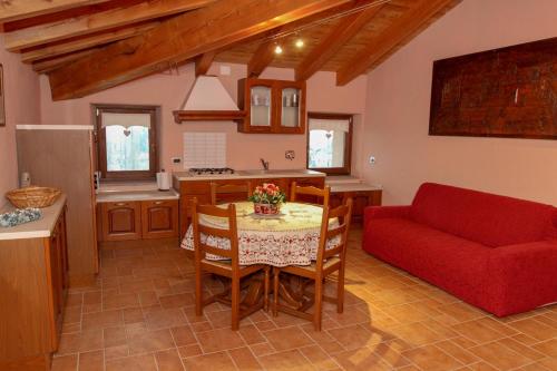 a living room with a table and a red couch at La Maison De Deni in Aymavilles