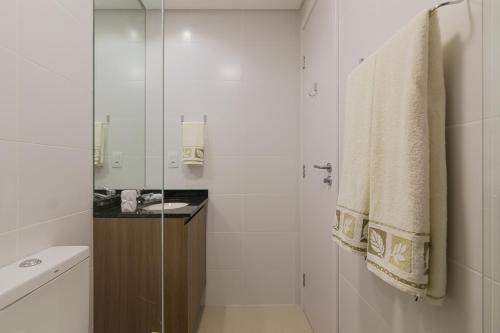 een witte badkamer met een wastafel en een spiegel bij Studio próximo ao shopping Curitiba, Wifi, TV a Cabo e Cozinha completa. in Curitiba