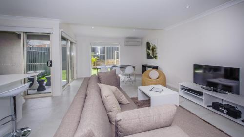 a living room with a couch and a flat screen tv at Escape At Nobbys Executive Townhouse 1 74 Pacific Drive in Port Macquarie