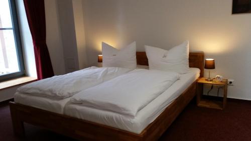a bedroom with a bed with white sheets and pillows at Pension Am Dorfanger in Hohennauen