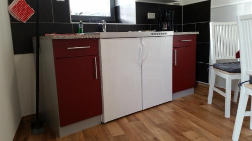 a kitchen with red and white cabinets and a sink at Pension Am Dorfanger in Hohennauen