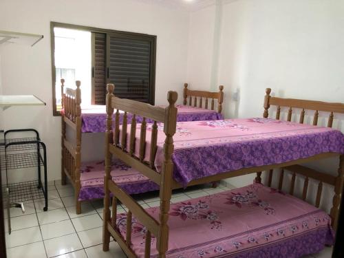 a bedroom with two bunk beds with purple sheets at Cobertura vista para o mar in Praia Grande