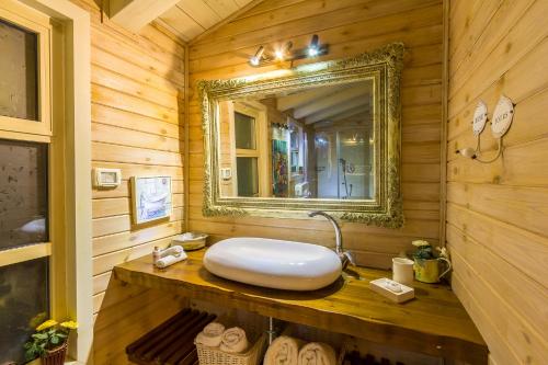 a bathroom with a sink and a mirror on a wooden wall at Betzel Ha'Ella in Kahal