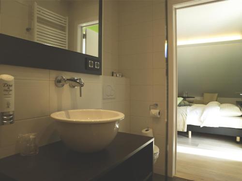 a bathroom with a sink and a mirror and a bed at Hotel Aulnenhof in Landen