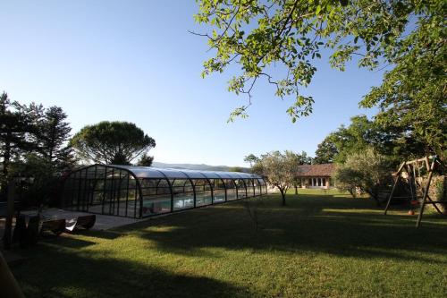 a glass greenhouse in a park with a playground at Chateau de Mauras in Chomérac