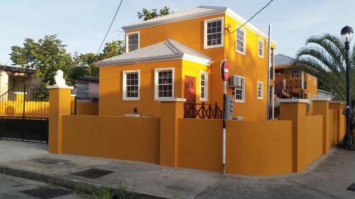 a yellow house with a fence in front of it at Frontline Apartments in Christ Church