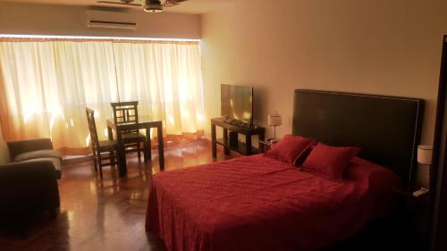 1 dormitorio con 1 cama con colcha roja en Corrientes Av, Premium Location en Buenos Aires