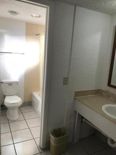 a bathroom with a toilet and a sink and a tub at Super Lodge Motel El Paso in El Paso