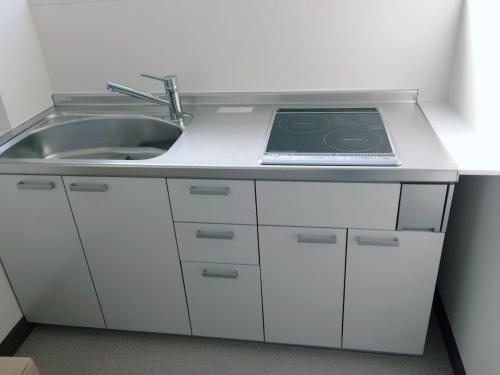 a kitchen with a sink and a stove at Business Hotel TenTen in Okayama