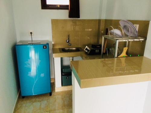 a kitchen with a blue refrigerator and a sink at D'uma Amed Homestay in Amed
