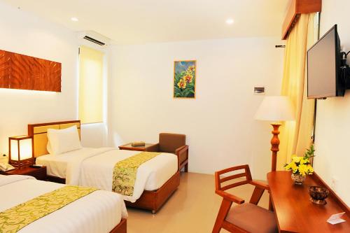 a hotel room with two beds and a desk at Kautaman Hotel in Mataram