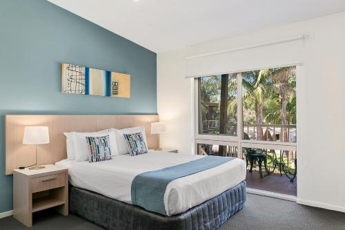 a bedroom with a bed and a large window at Kaloha Holiday Resort Phillip Island in Cowes