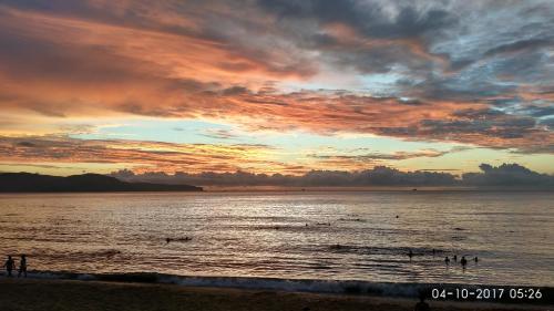 a sunset at the beach with people in the water at Sun Sea Hotel in Quy Nhon