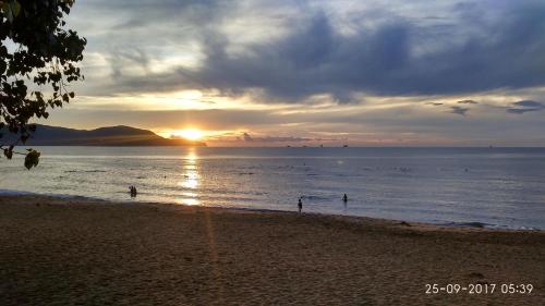 a sunset on a beach with people in the water at Sun Sea Hotel in Quy Nhon