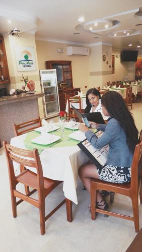 two women sitting at a table playing a keyboard at Hotel Perla Verde in Volcán Chimborazo